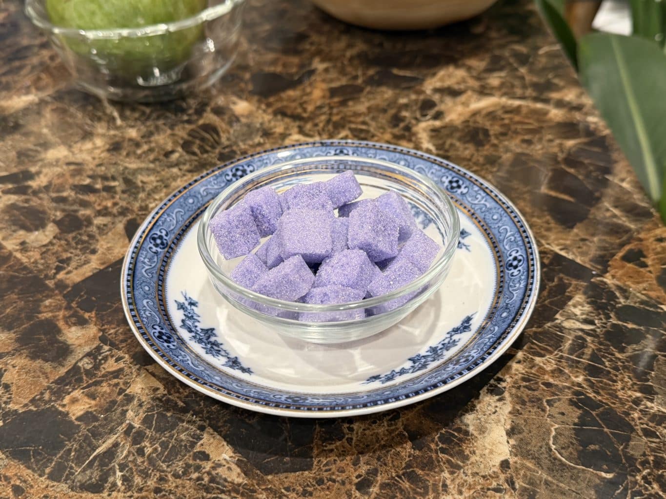 Purple Sugar Cubes in a clear bowl on a blue and gold saucer