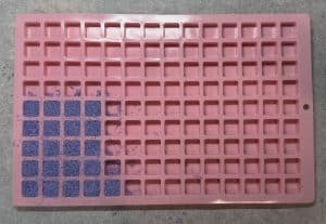 Purple sugar pressed into partially filled pink cube mold
